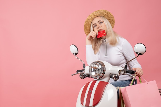 Vista frontal señorita con sombrero de Panamá en ciclomotor con tarjeta