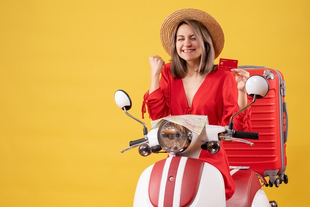 Vista frontal de la señorita con sombrero de Panamá con tarjeta bancaria en ciclomotor