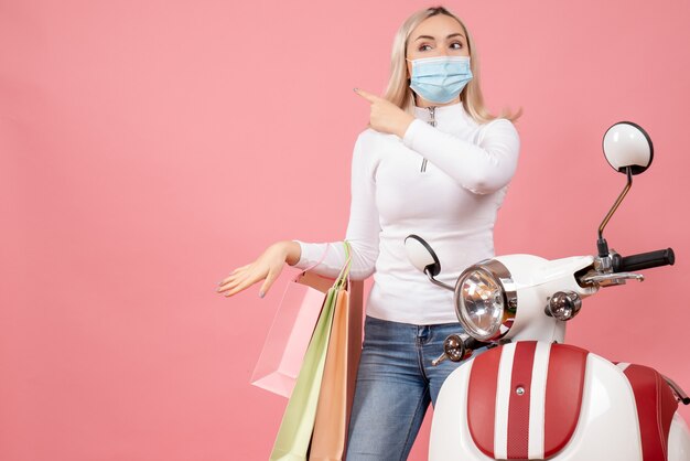 Vista frontal señorita sosteniendo bolsas de compras cerca de ciclomotor