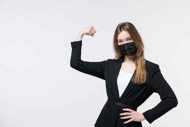 Vista frontal de la señorita en traje con mascarilla quirúrgica y disfrutando de su éxito en blanco