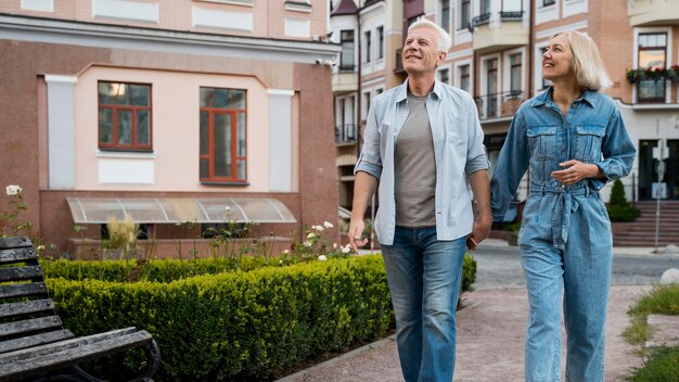 Vista frontal si la pareja de ancianos cogidos de la mano en la ciudad