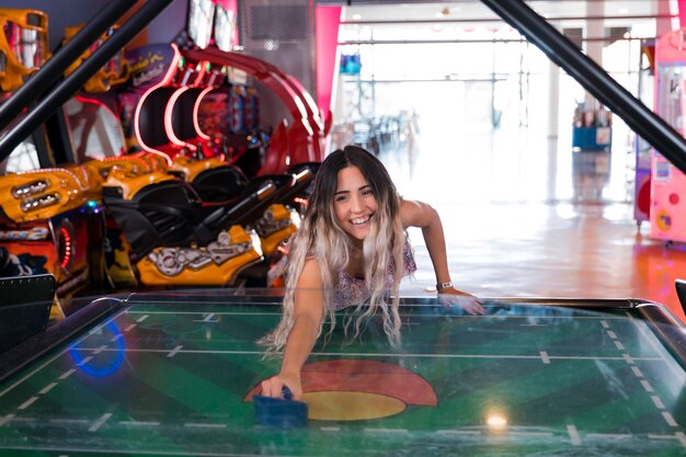 Vista frontal smilling mujer jugando air hockey