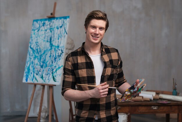 Vista frontal sonriente hombre mezclando diferentes colores para su pintura