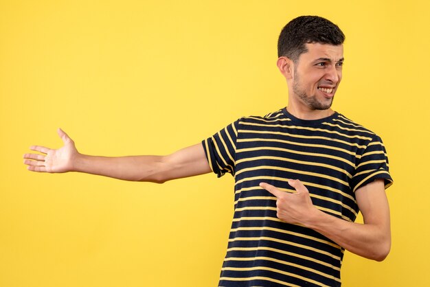 Vista frontal sonriente joven en camiseta a rayas blanco y negro fondo amarillo aislado