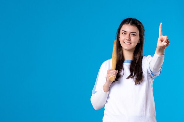 Vista frontal sonriente joven mujer con bate de béisbol