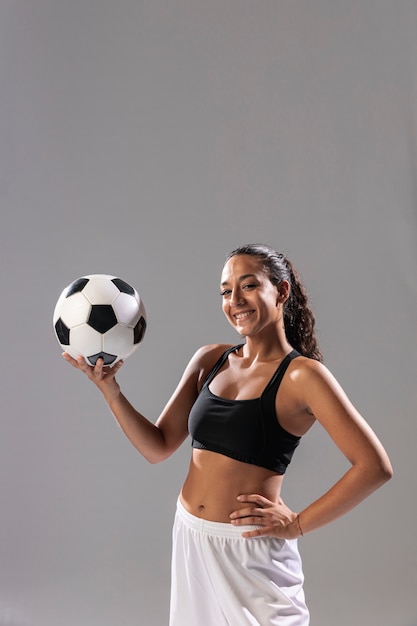 Vista frontal sonriente mujer con balón de fútbol