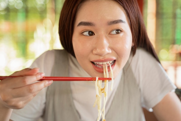 Vista frontal sonriente mujer comiendo fideos