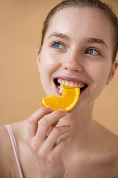 Vista frontal sonriente mujer comiendo naranja