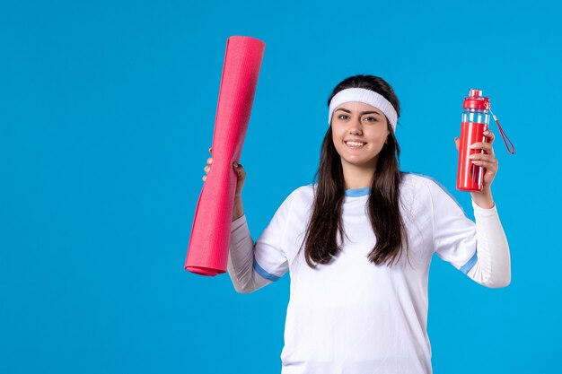 Vista frontal sonriente mujer joven con estera de yoga