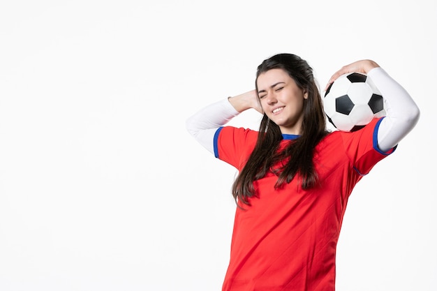 Vista frontal sonriente mujer joven en ropa deportiva con balón de fútbol