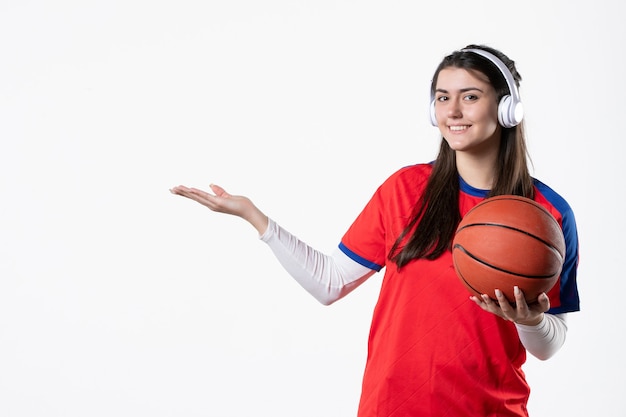 Vista frontal sonriente mujer joven en ropa deportiva con baloncesto