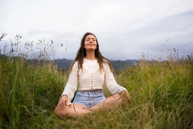 Vista frontal sonriente mujer meditando al aire libre