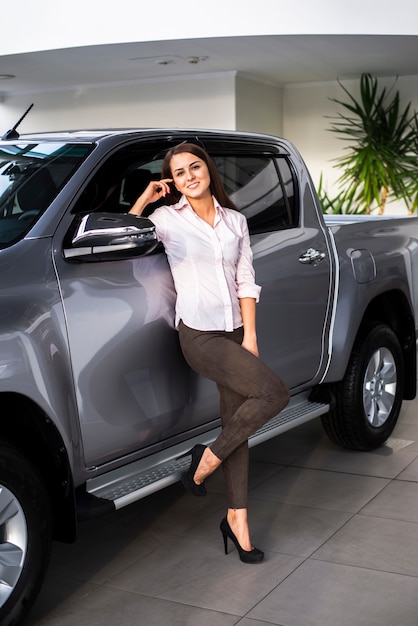 Vista frontal sonriente mujer posando junto al coche