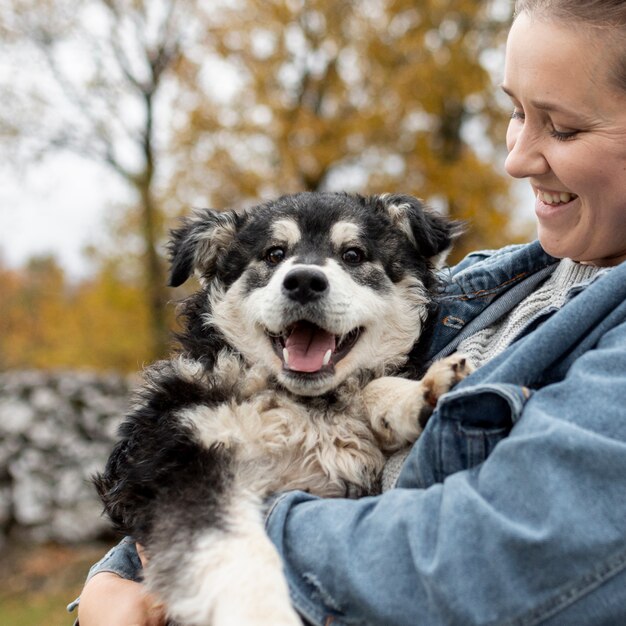 Vista frontal sonriente mujer sosteniendo lindo perro