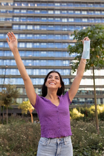 Foto gratuita vista frontal sonriente mujer sosteniendo máscara