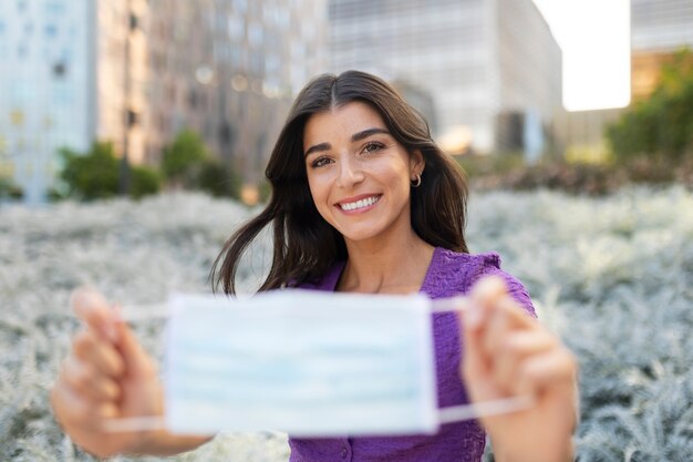 Vista frontal sonriente mujer sosteniendo máscara