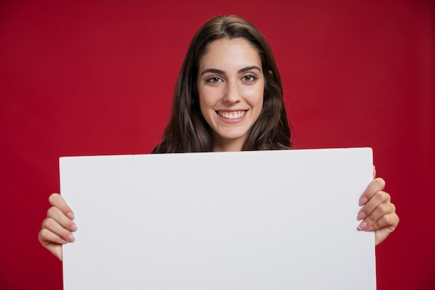 Vista frontal sonriente mujer sosteniendo una pancarta vacía