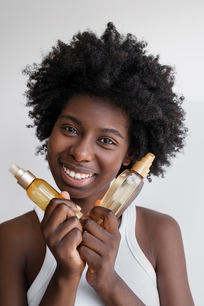 Vista frontal sonriente mujer sosteniendo productos para el cabello