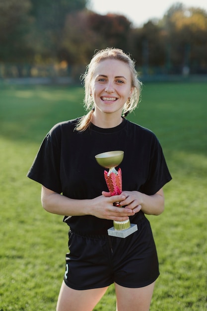 Vista frontal sonriente mujer sosteniendo un trofeo