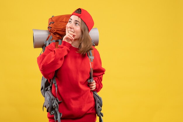 Vista frontal sonriente mujer viajera con mochila mirando algo