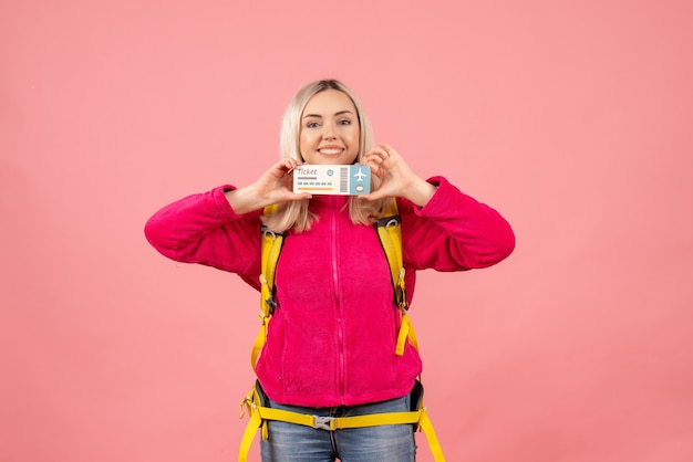 Vista frontal sonriente mujer viajera en ropa casual con mochila con boleto