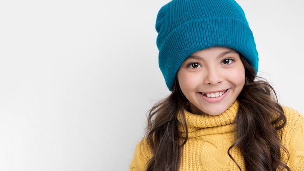 Vista frontal sonriente niña con sombrero de invierno