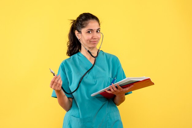 Vista frontal sonrió a la doctora con estetoscopio de pie sobre fondo amarillo