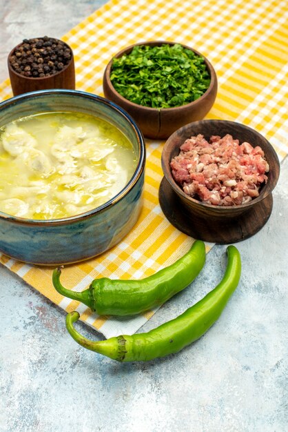 Vista frontal de la sopa de albóndigas dushbara en un tazón de fuente de pimientos picantes con carne, pimienta y verduras sobre fondo desnudo