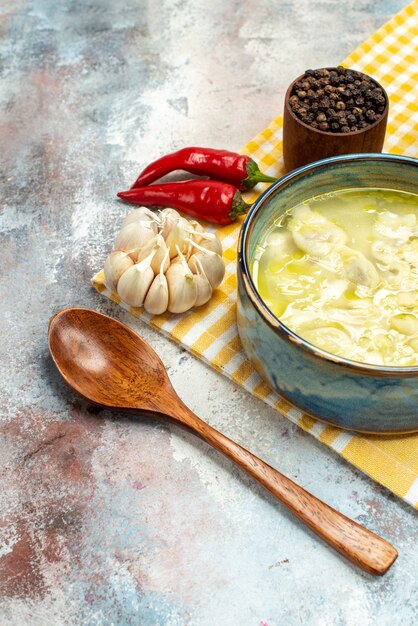 Vista frontal de la sopa de bolas de masa hervida dushbara en un tazón de ajo pimientos picantes cuchara de madera sobre fondo desnudo