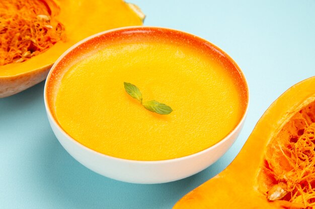 Vista frontal de la sopa de calabaza con calabazas frescas en la sopa de color de plato de mesa azul