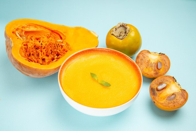 Vista frontal de la sopa de calabaza con calabazas frescas en la sopa de color de plato de mesa azul