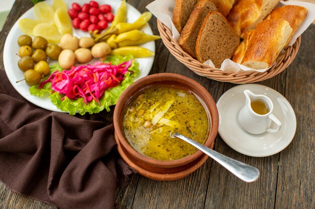 Una vista frontal sopa caliente junto con verduras frescas y rebanadas de pan