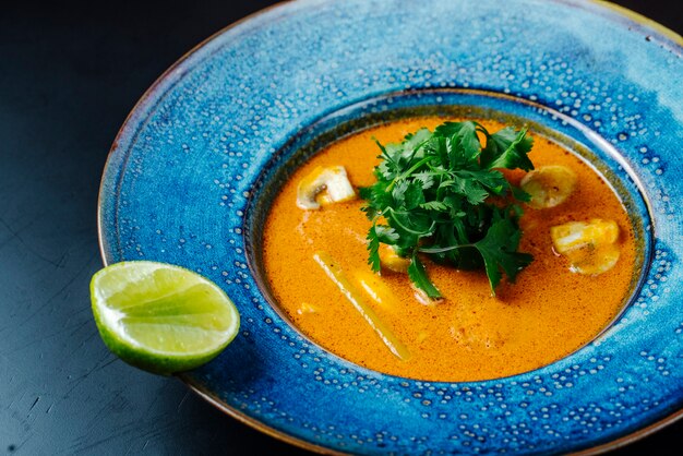 Vista frontal sopa con champiñones y hierbas con una rodaja de limón en un plato