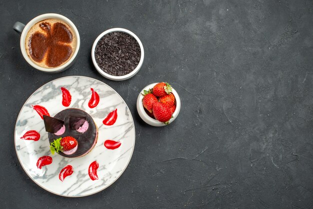 Vista frontal de tarta de queso de fresa en cuencos de placa ovalada blanca con fresas y chocolate una taza de café sobre fondo oscuro espacio libre