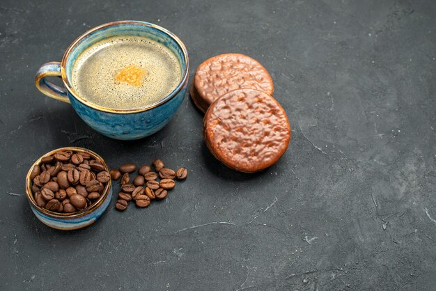 Foto gratuita vista frontal de una taza de café con galletas de semillas de café en lugar oscuro libre