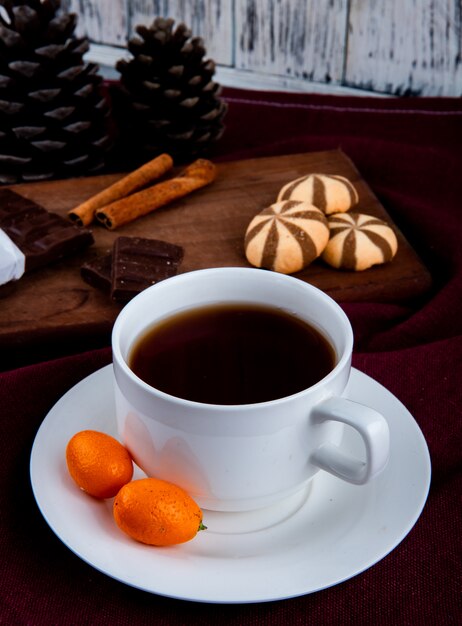 Vista frontal taza de café con kumquat y galletas con chocolate