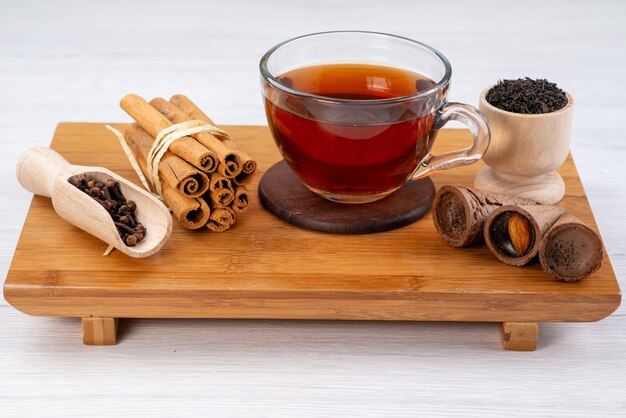 Vista frontal de una taza de té con canela y cuernos en dulces de postre de té de madera marrón