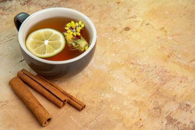 Vista frontal de una taza de té con canela y limón en la mesa de luz