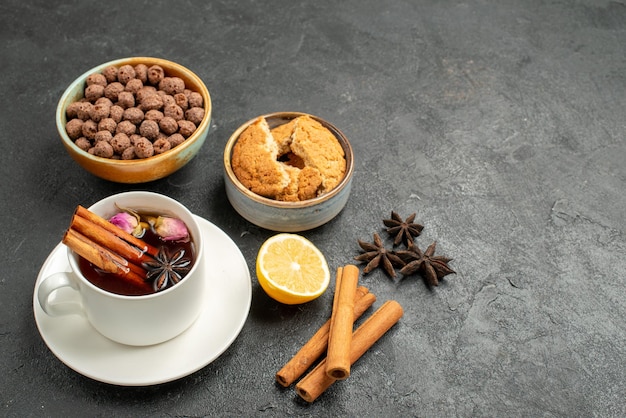 Vista frontal de la taza de té con canela sobre el fondo gris oscuro ceremonia de bebida de té dulce