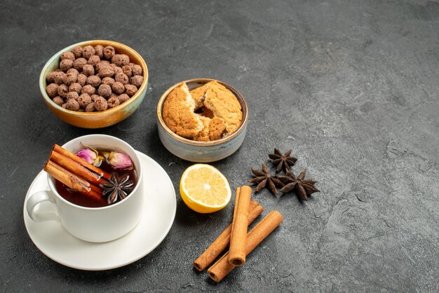 Vista frontal de la taza de té con canela sobre el fondo gris oscuro ceremonia de bebida de té dulce