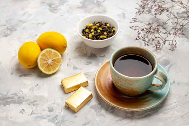 Vista frontal de una taza de té con caramelos y limón en el espacio en blanco