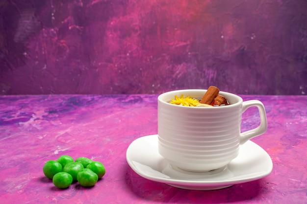 Foto gratuita vista frontal de la taza de té con caramelos verdes en el caramelo de color rosa té de mesa