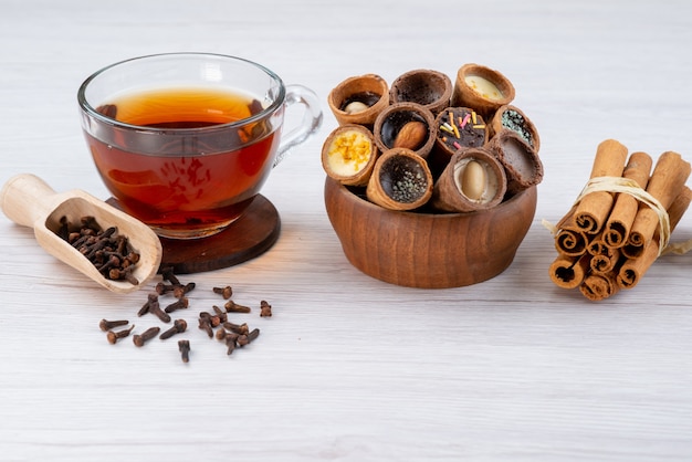 Vista frontal de una taza de té con cuernos y canela en blanco, postre de desayuno de té