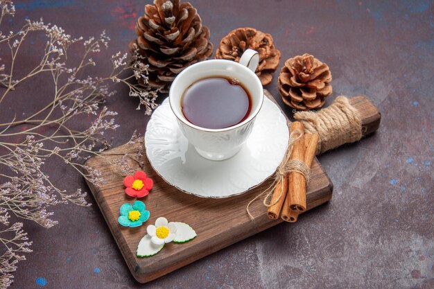 Vista frontal de la taza de té dentro de la taza de vidrio con placa en el escritorio oscuro té ceremonia de oscuridad de color