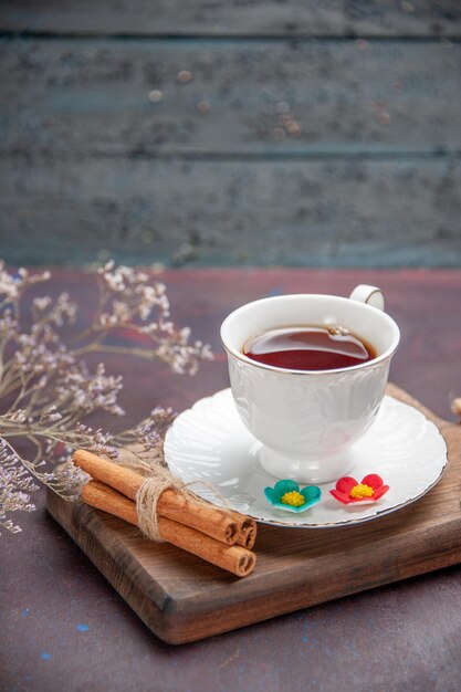 Vista frontal de la taza de té dentro de la taza de vidrio con placa en el espacio oscuro