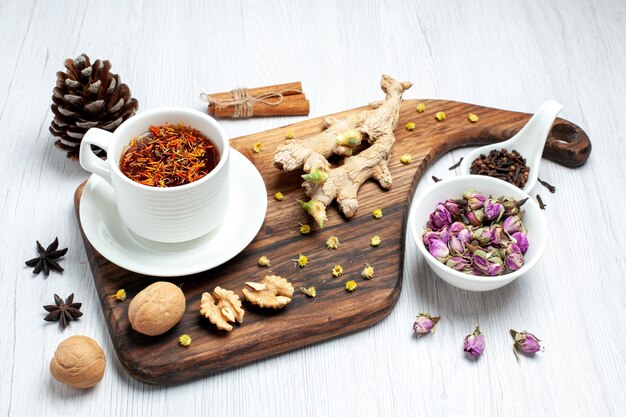 Vista frontal de la taza de té con flores secas y nueces sobre fondo blanco té bebida tuerca