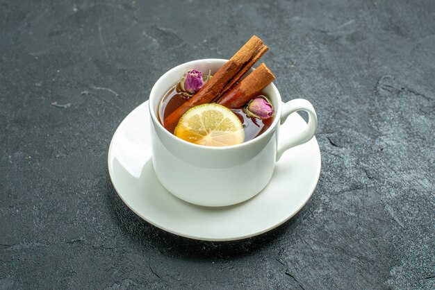 Vista frontal de la taza de té con flores y té en la ceremonia de cítricos de frutas de té de superficie oscura