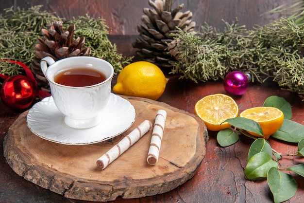 Vista frontal de una taza de té con frutas sobre fondo oscuro