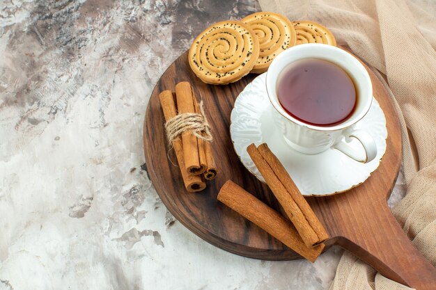 Vista frontal taza de té con galletas dulces sobre fondo claro ceremonia de descanso de galletas colores de pastel de café con azúcar