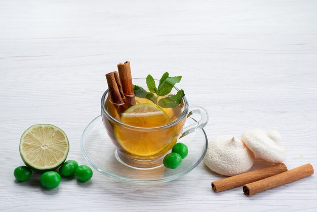 Vista frontal de una taza de té con galletas de limón y canela en blanco, dulces de postre de té